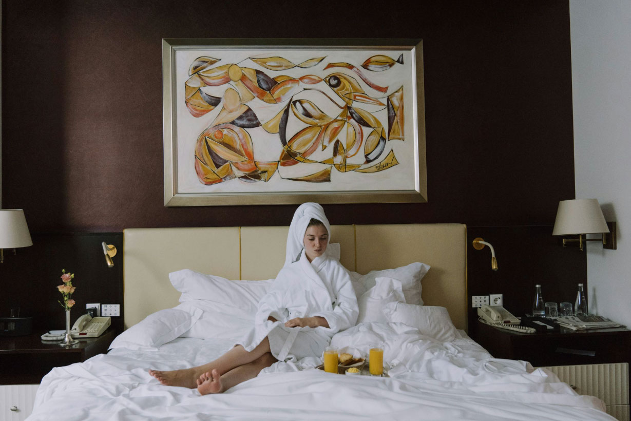 Why hotel connectivity can make or break your luxury property body image showing a guest relaxing on a bed eating breakfast